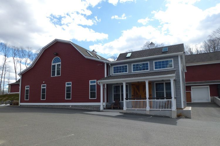 A large red barn shaped house with a white porch
