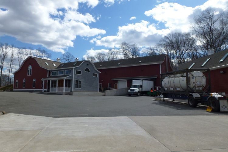 A truck is parked in front of a large red barn