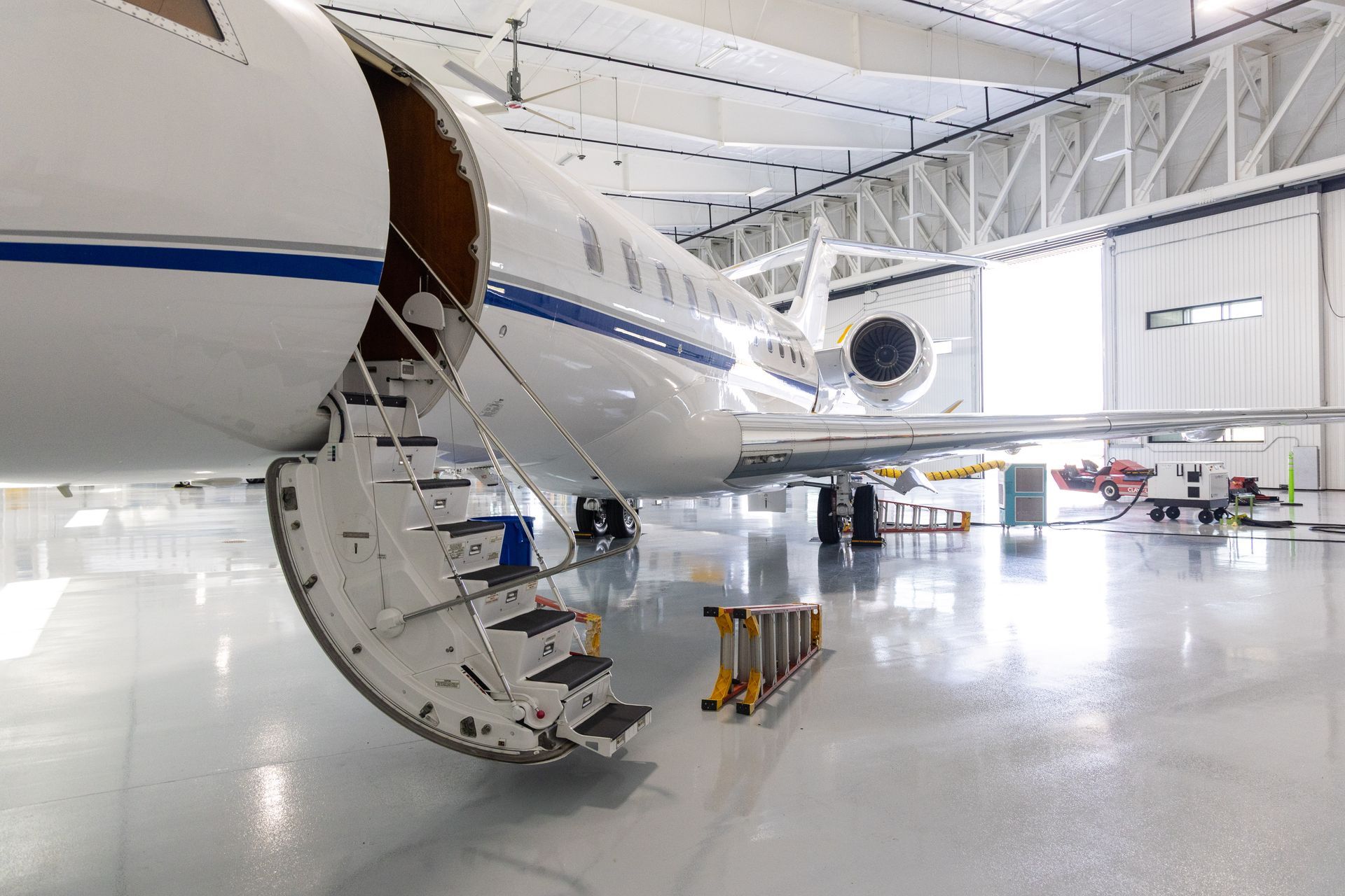 A private jet with its door open, steps extended, parked inside a hangar.