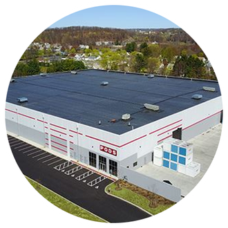 An aerial view of a large white building with a black roof.