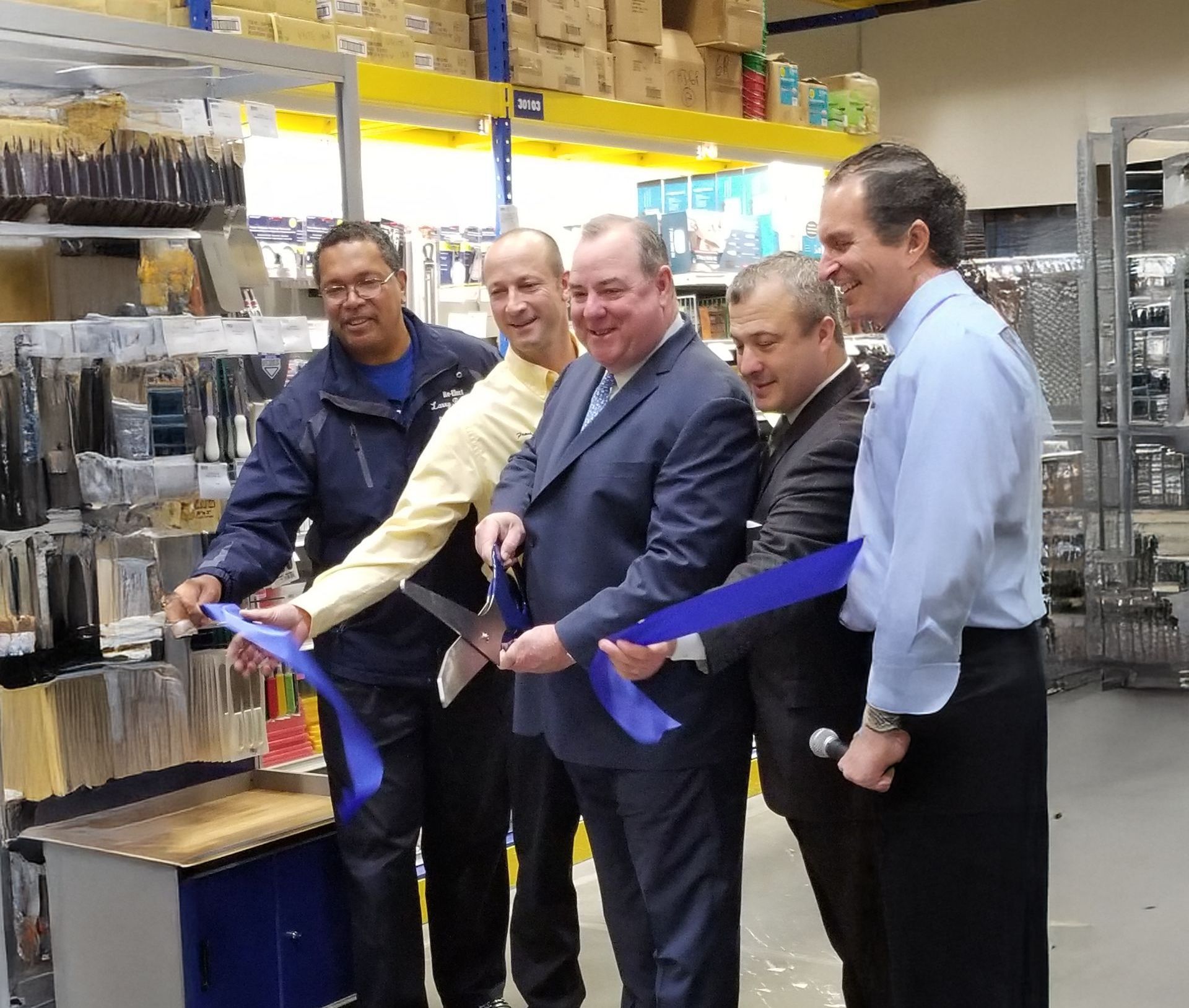A group of men are cutting a blue ribbon in a store