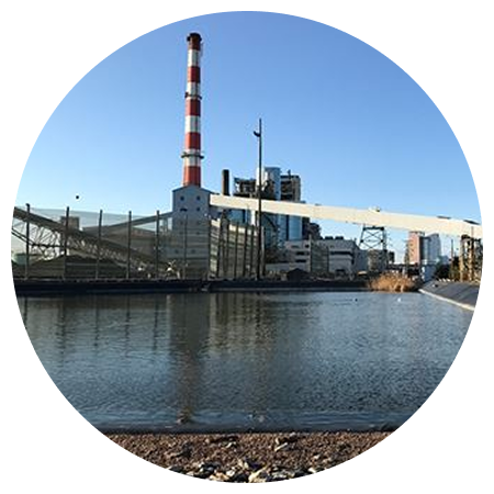 A red and white striped power plant sits next to a body of water