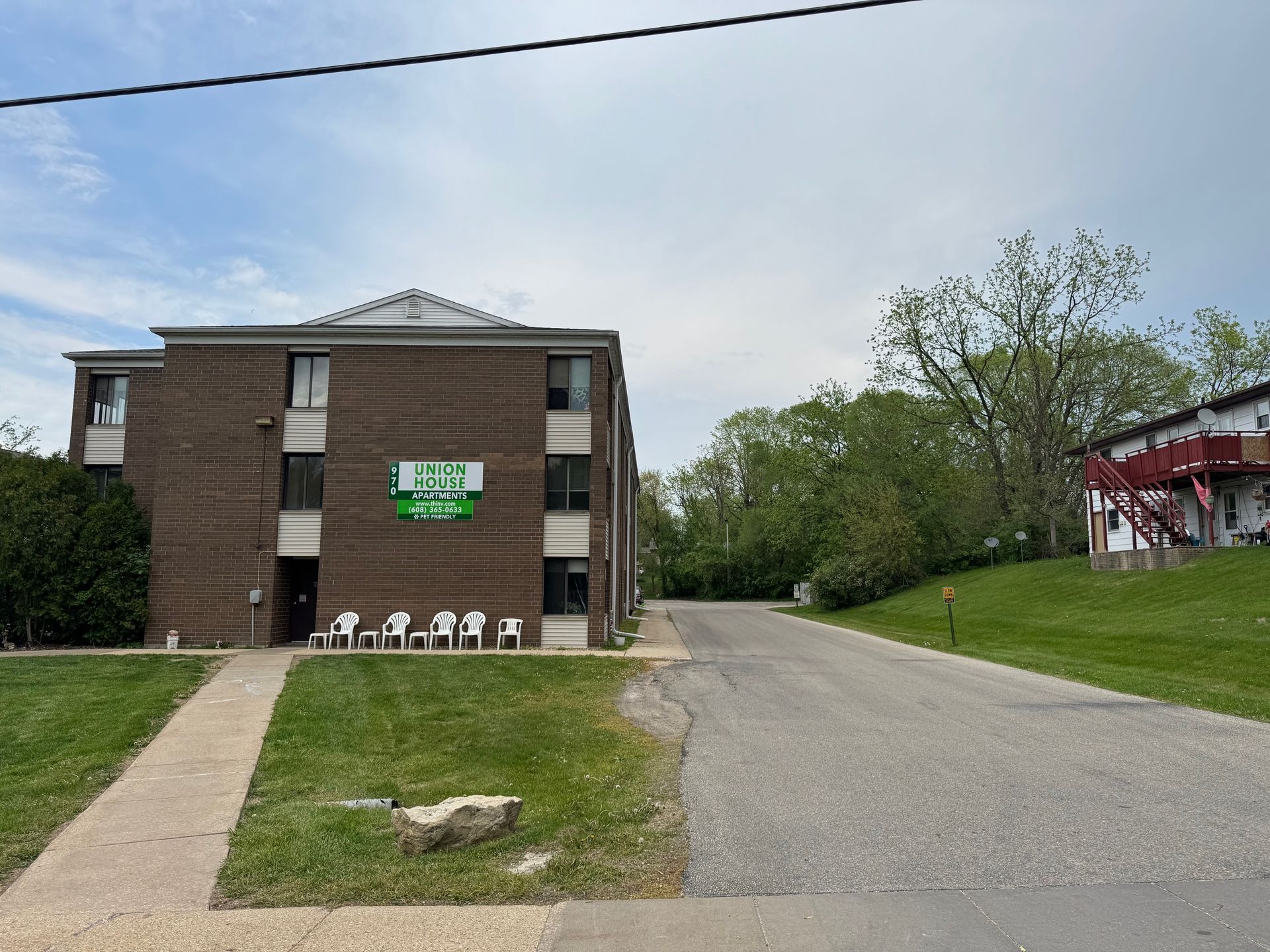 A brick apartment building with a green sign on the side of it