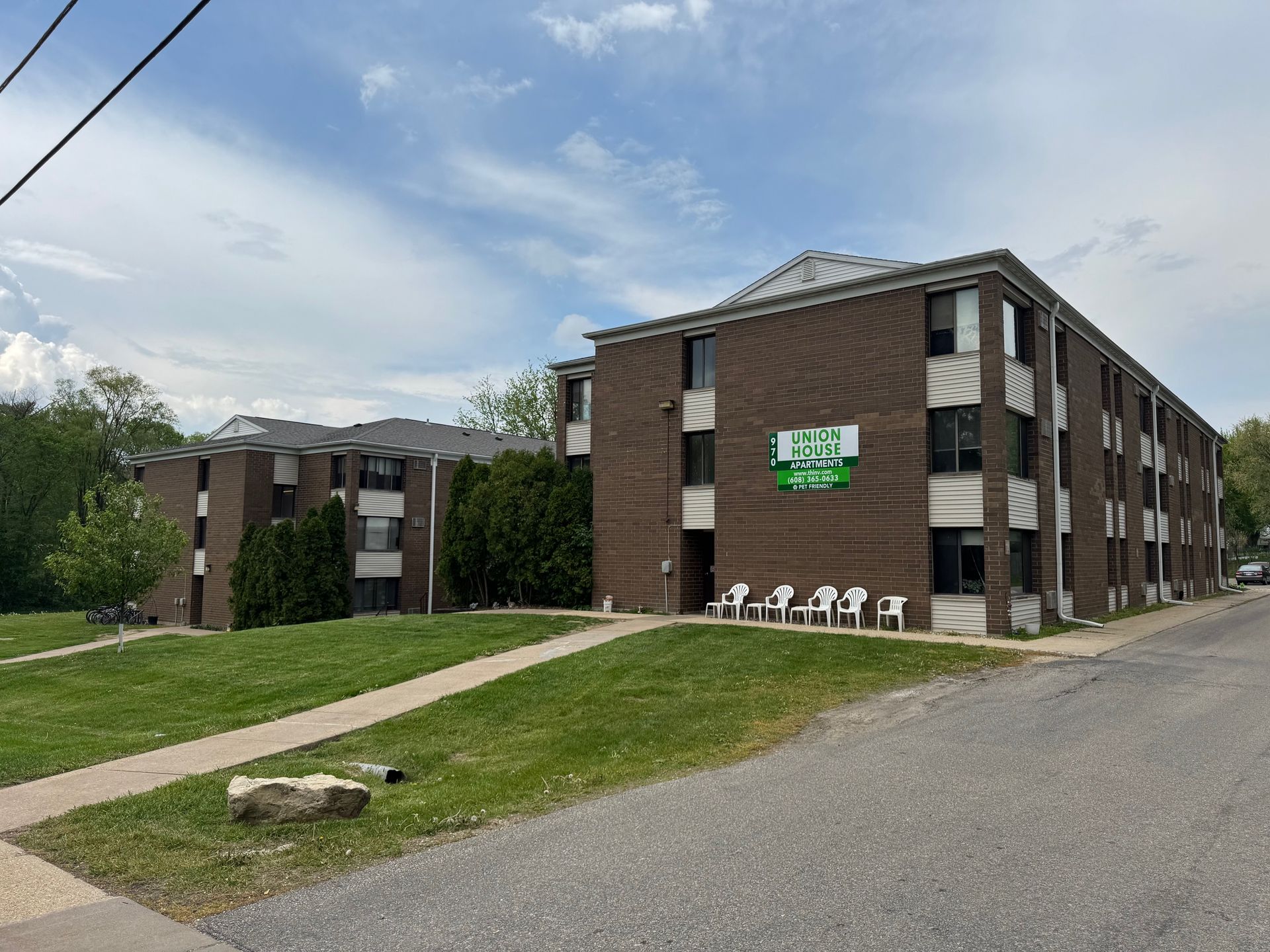A brick apartment building with a green sign on the side of it.