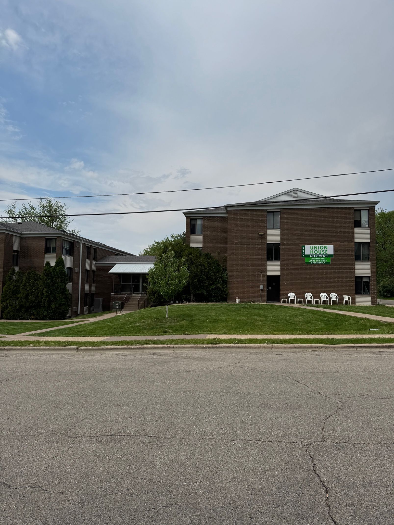 A large brick building with a green sign on the side of it.
