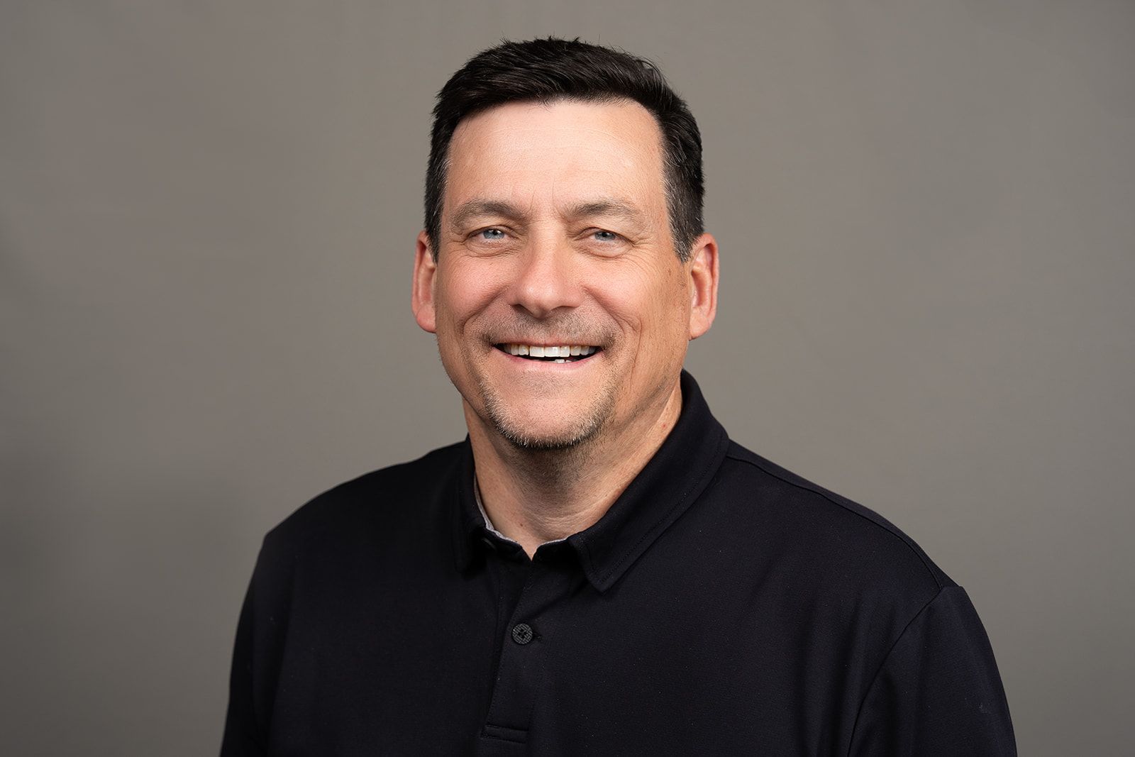 A man in a black shirt is smiling for the camera.