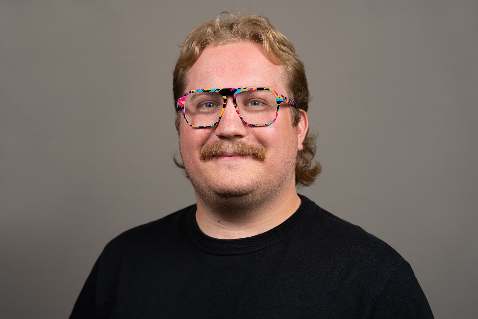 A man with glasses and a mustache is smiling for the camera.