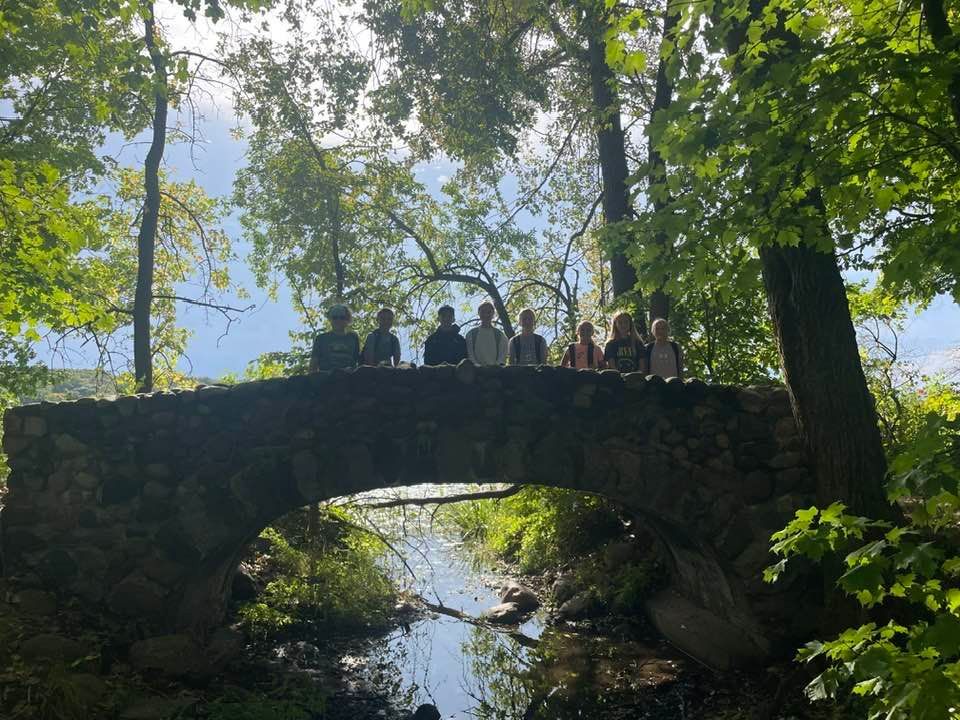 A group of people are standing on a stone bridge over a river.