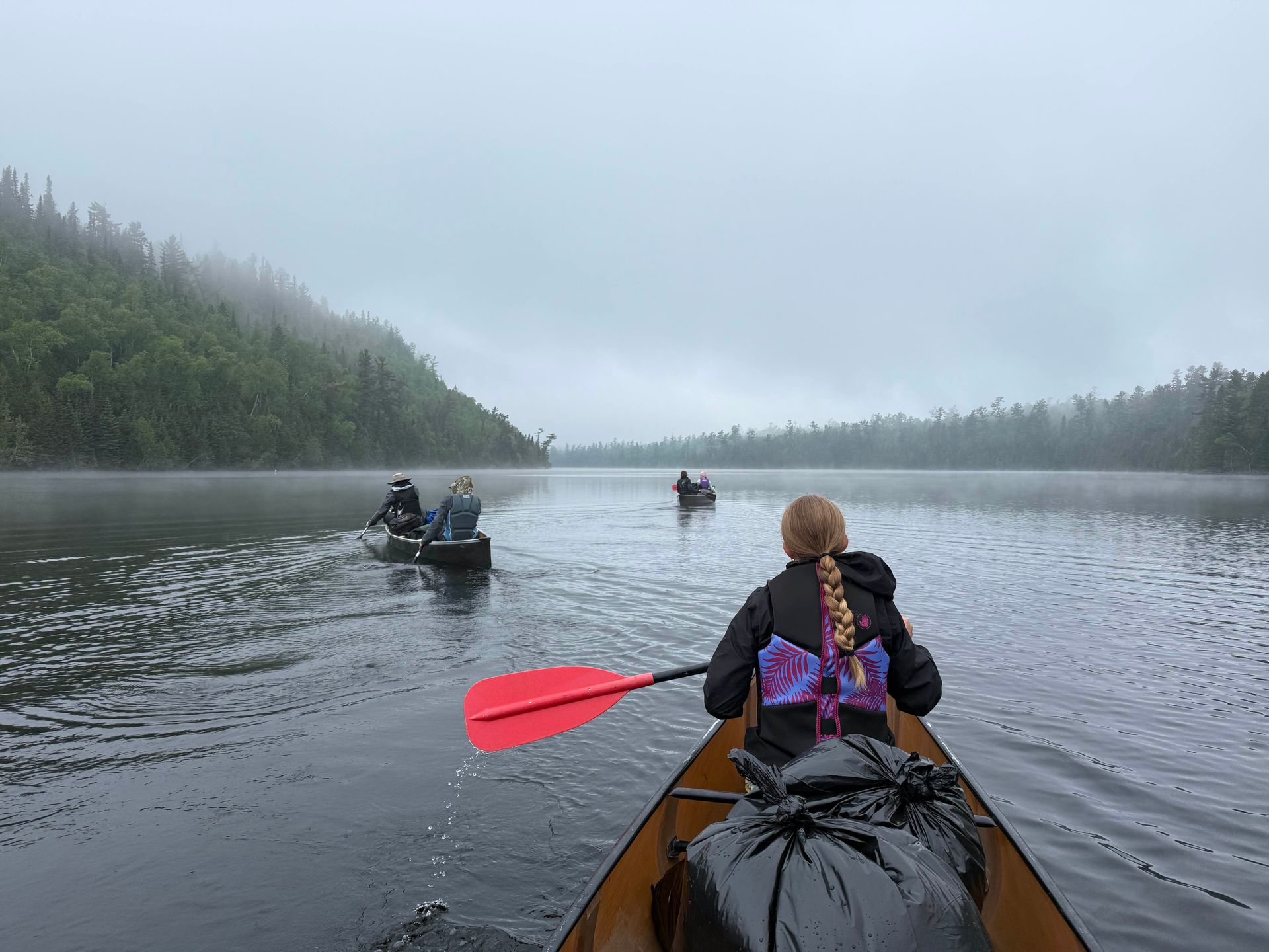 A woman is paddling a canoe on a lake.