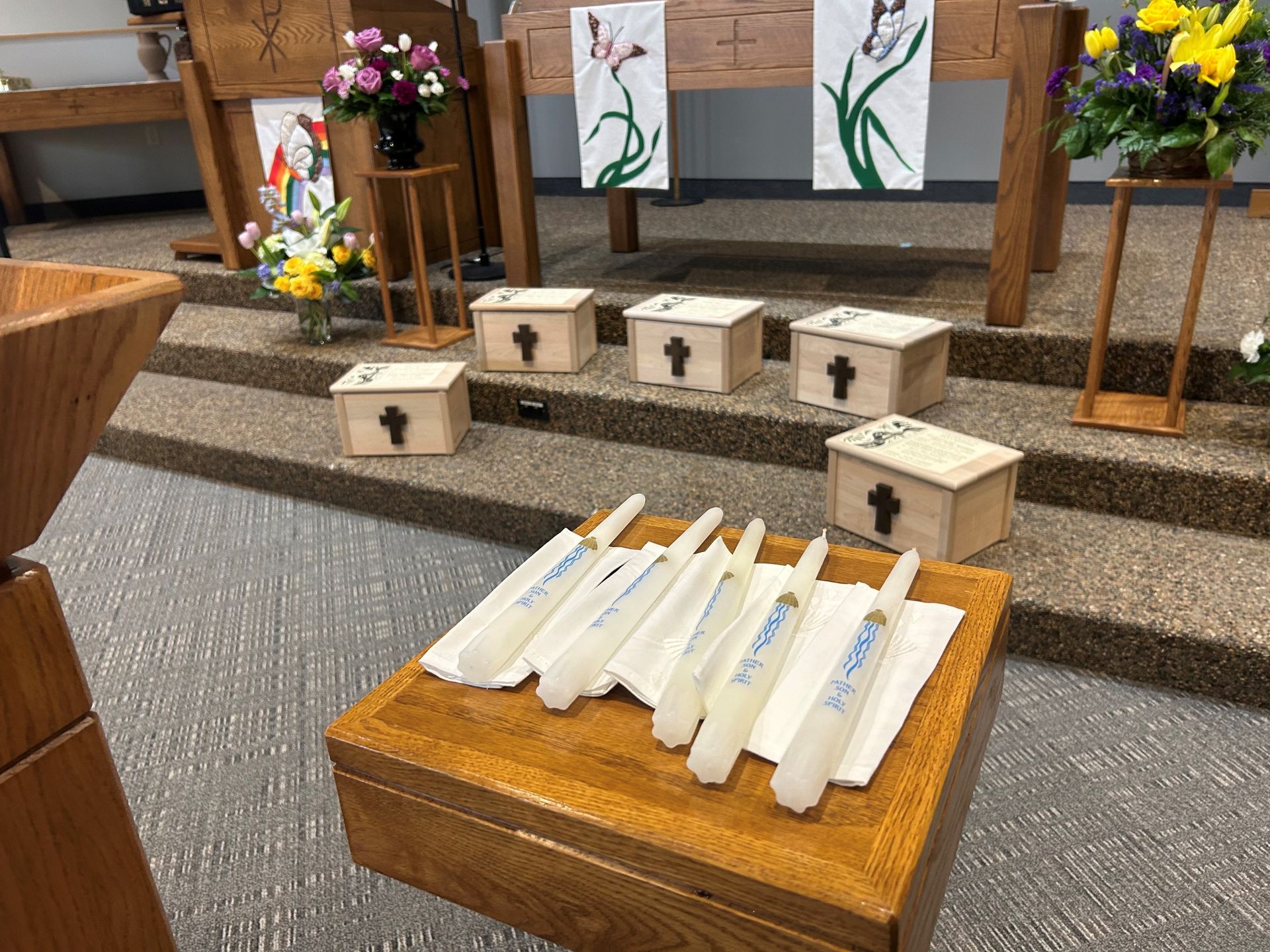 A bunch of candles are sitting on a wooden table in a church.
