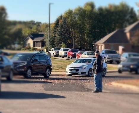 A couple of people are standing next to a car in a parking lot.