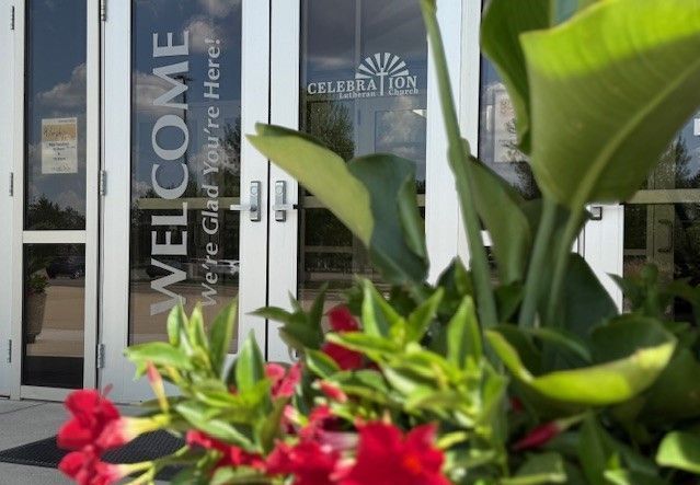A welcome sign is on the glass door of a building