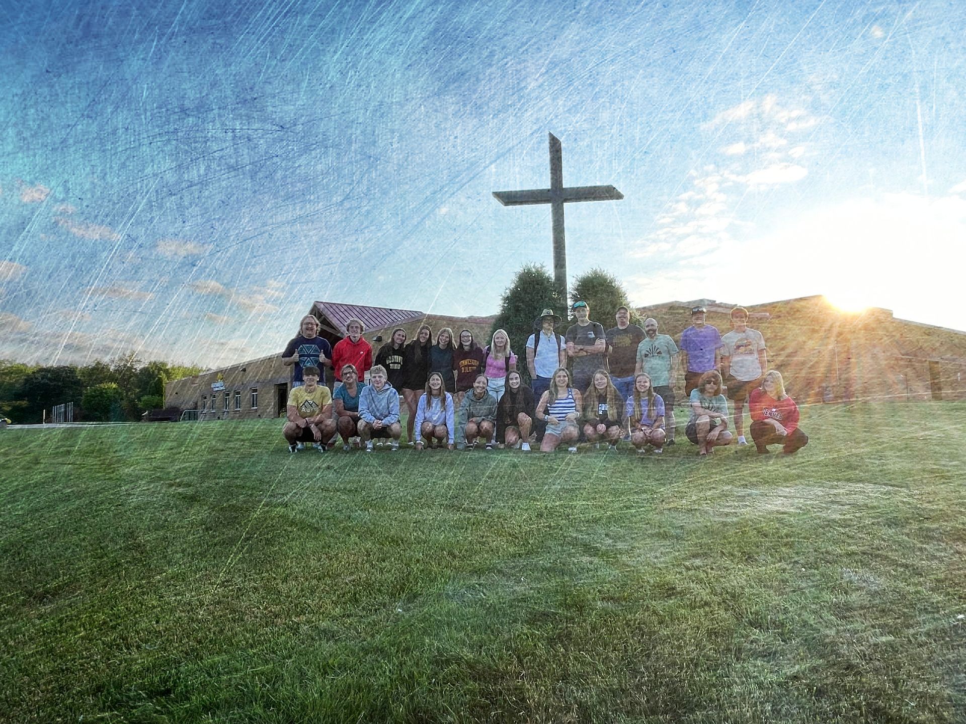 A group of people are posing for a picture in front of a cross.