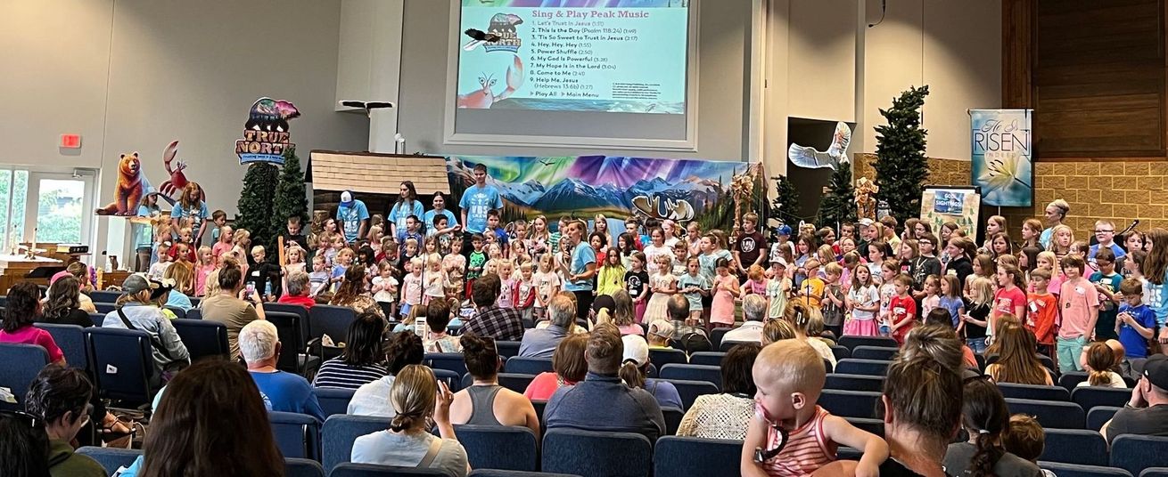 A large group of people are sitting in a church watching a presentation.