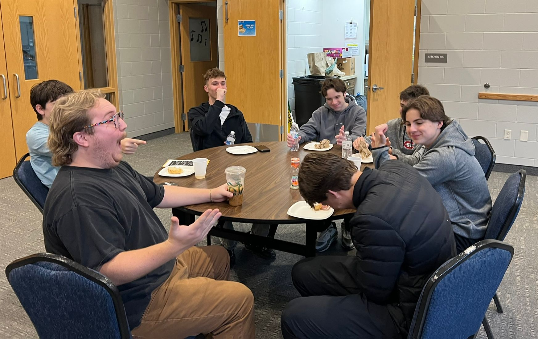People gather around a table in a church, looking at items. A wooden cross hangs on the wall.