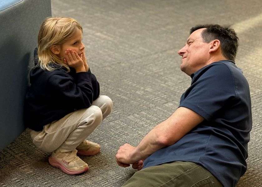 Autumn floral arrangement in front of a school entrance, featuring orange and yellow flowers and a white pumpkin.