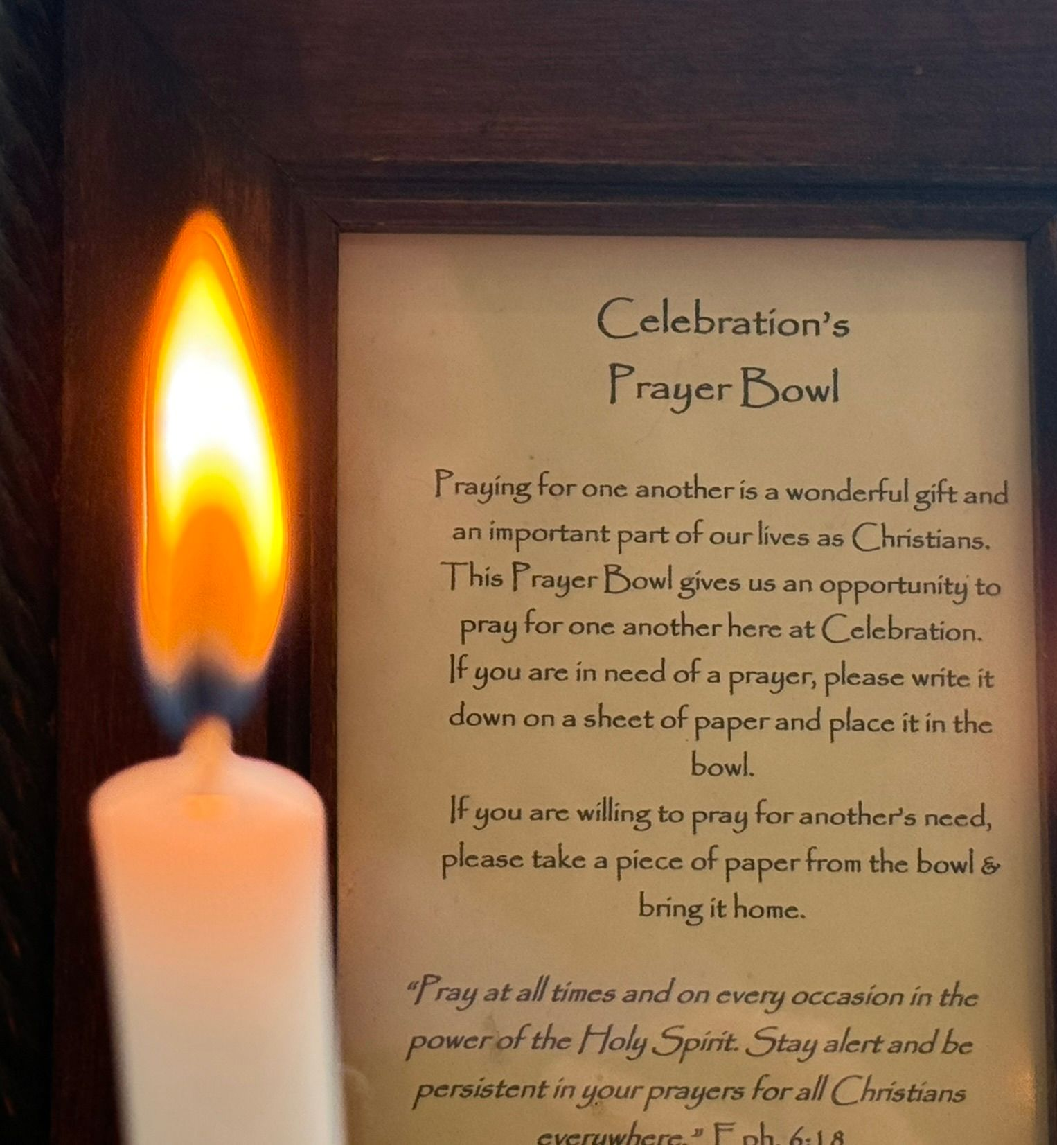 A candle is lit in a bowl of sand