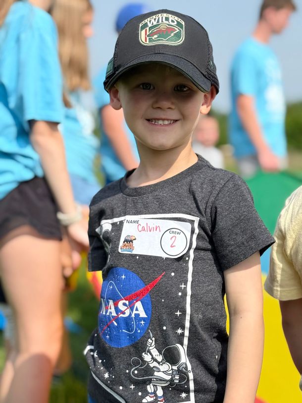 A young boy wearing a nasa shirt and a hat