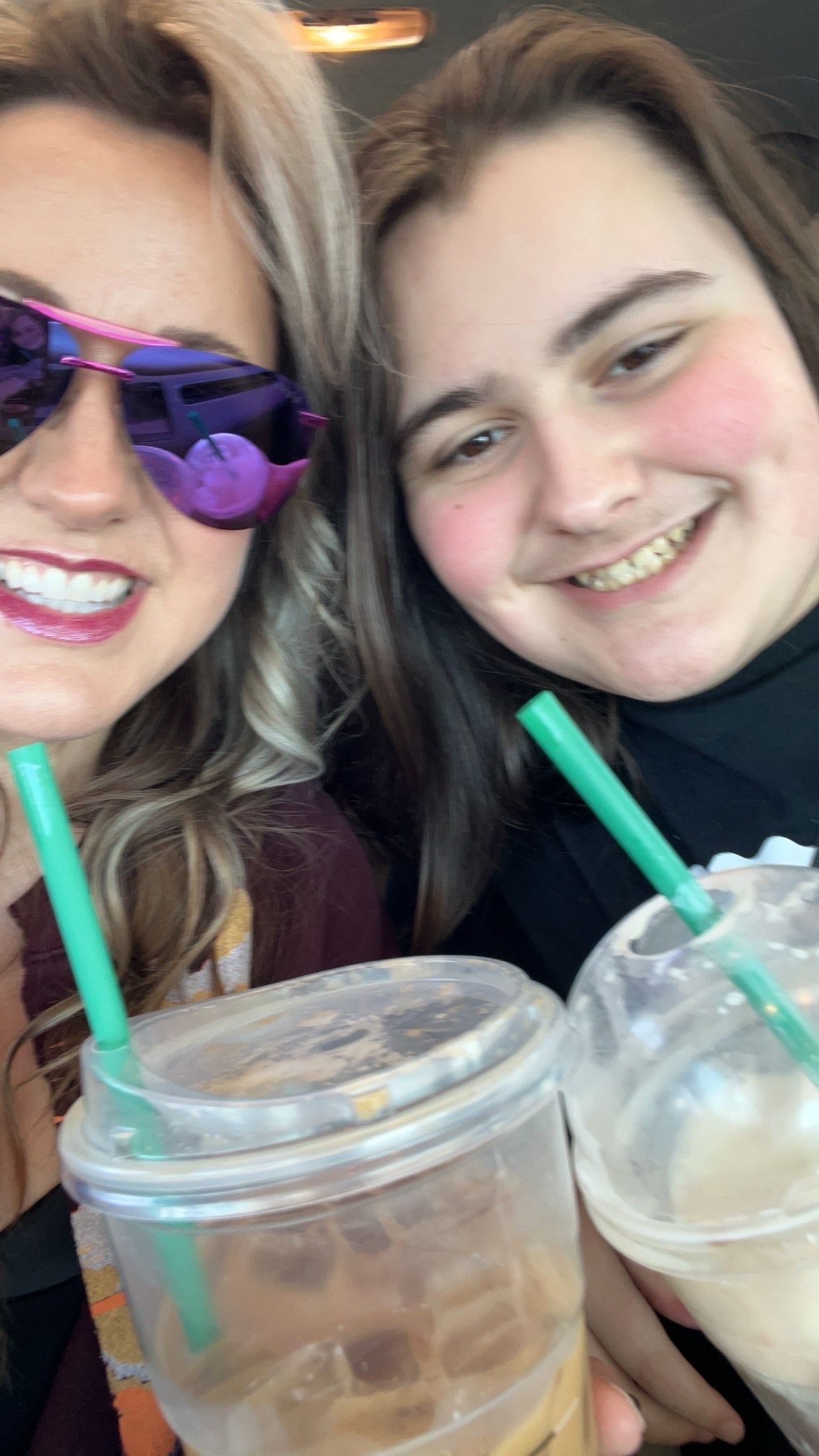 A woman and a boy are posing for a picture while drinking Starbucks coffee.