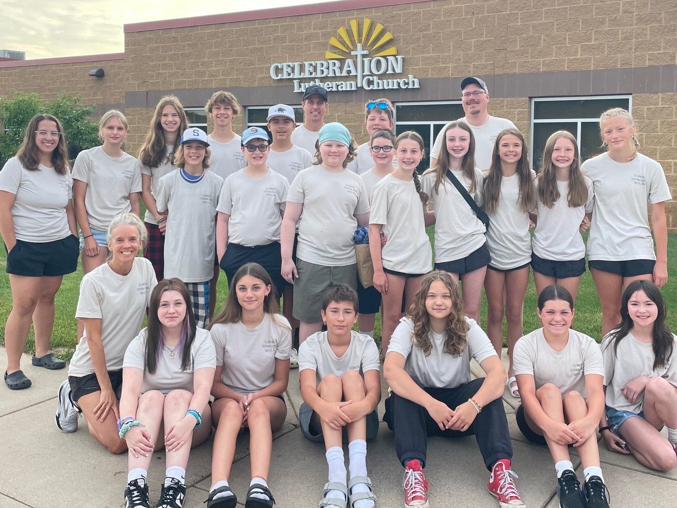 A group of young people wearing yellow vests are posing for a picture.