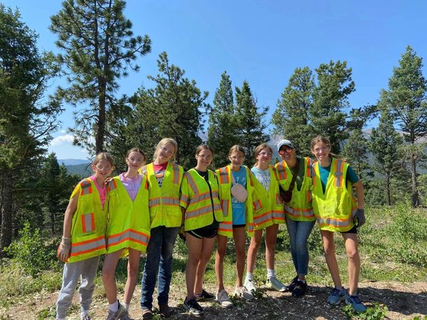 A group of young people wearing yellow vests are posing for a picture.