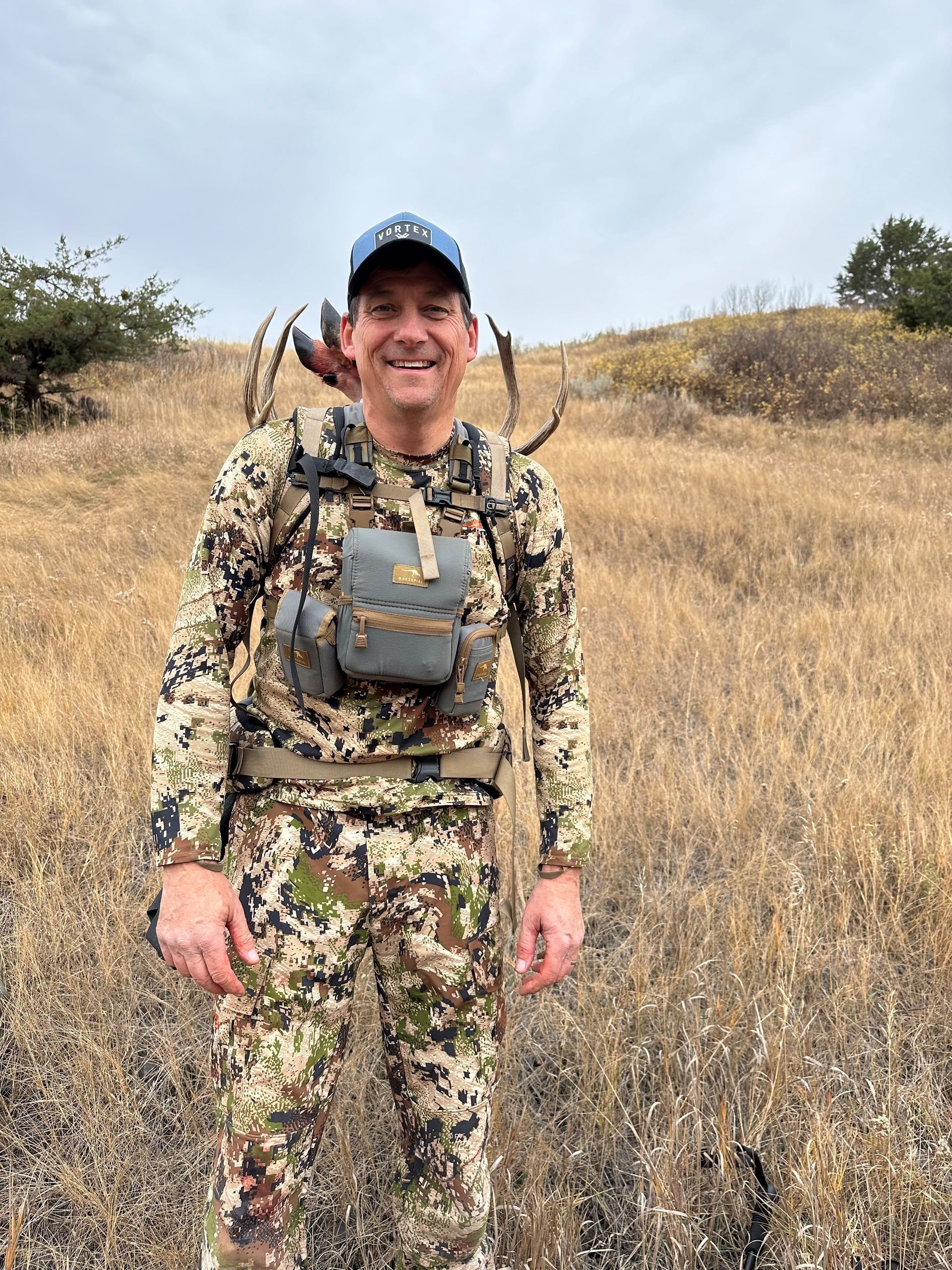 A man in a camouflage uniform is standing in a field.