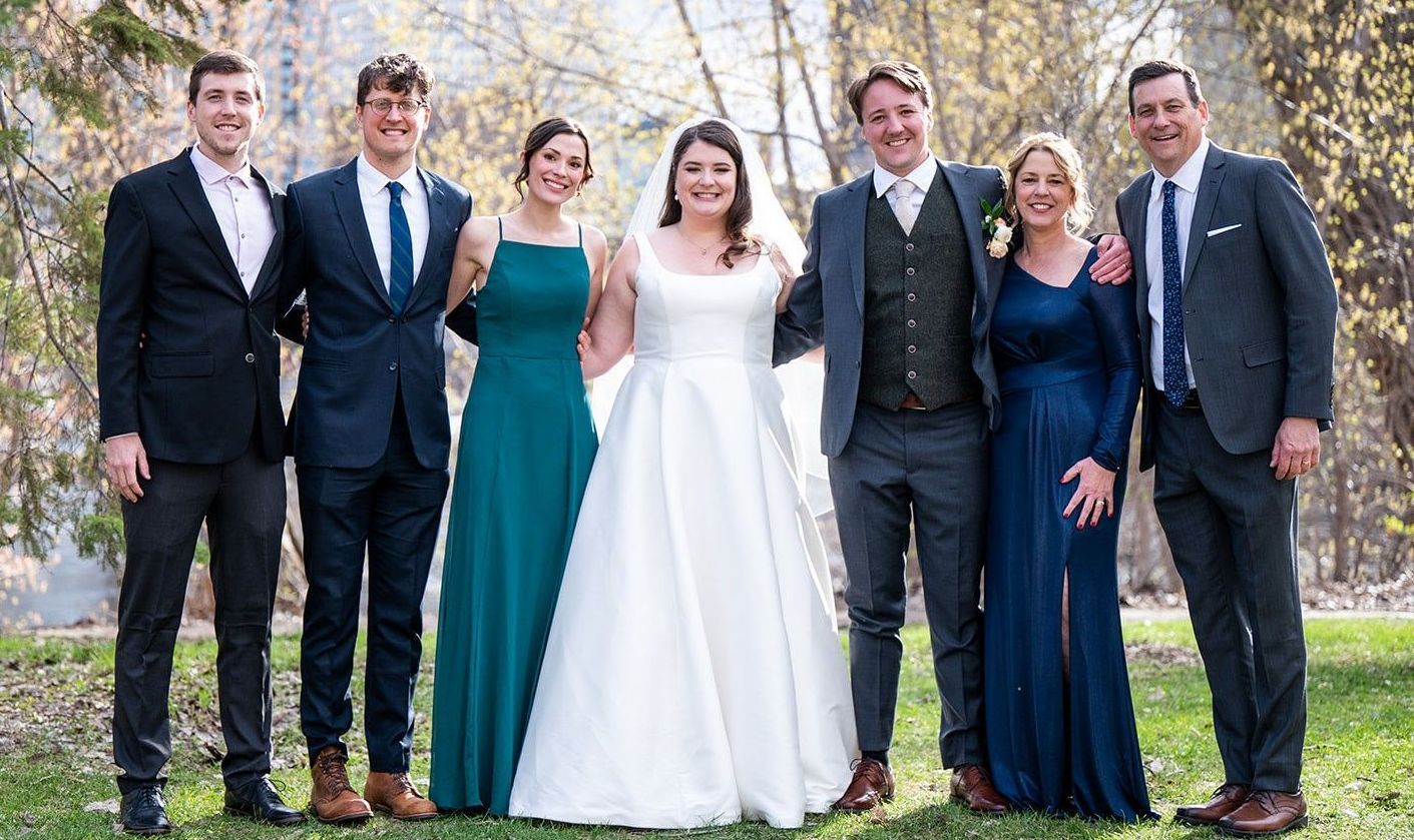 A bride and groom are posing for a picture with their wedding party.