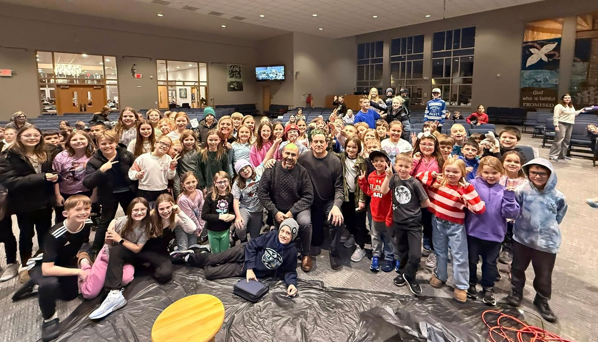 A large group of people are sitting in a church watching a presentation.