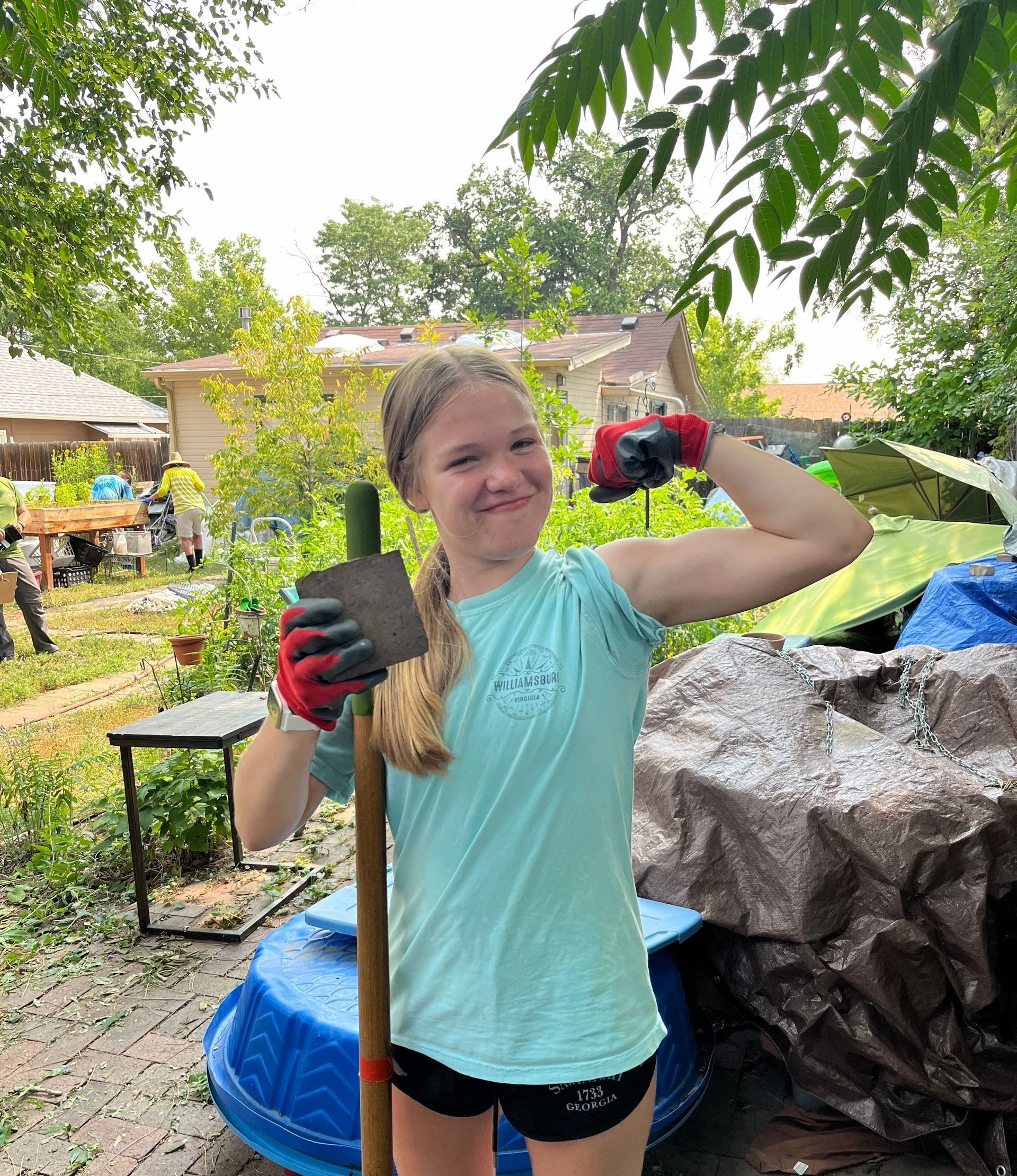 A young woman is holding a shovel and a piece of wood.