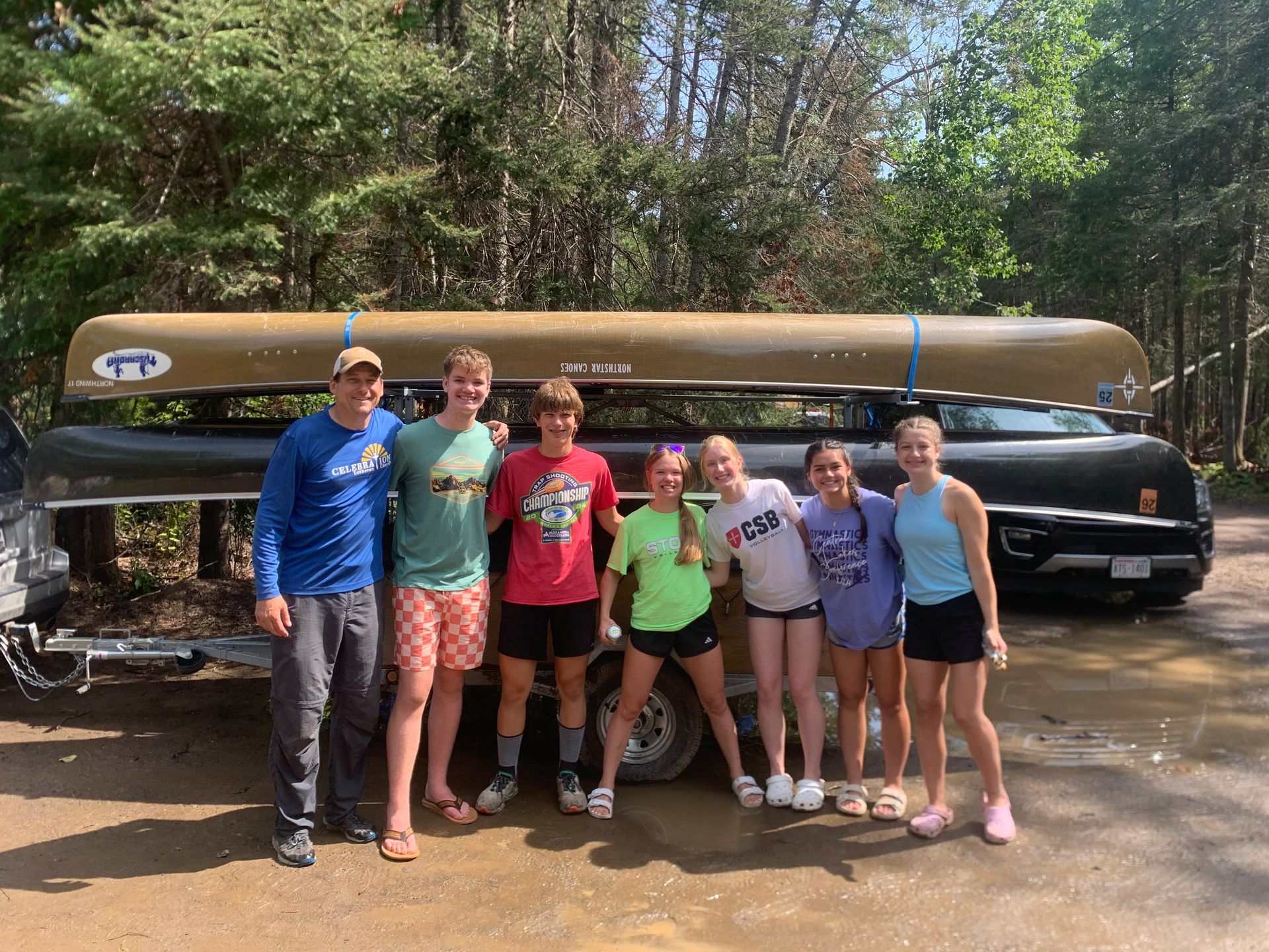 A group of people are posing for a picture in front of a canoe.