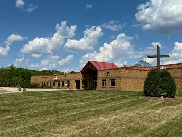A church with a cross in front of it on a sunny day
