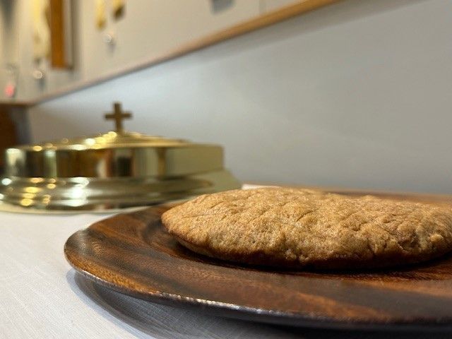 A cookie on a wooden plate with a cross in the background