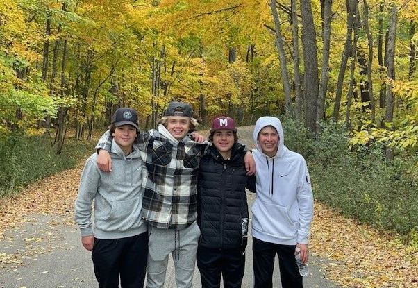 A group of young men are standing next to each other on a path in the woods.