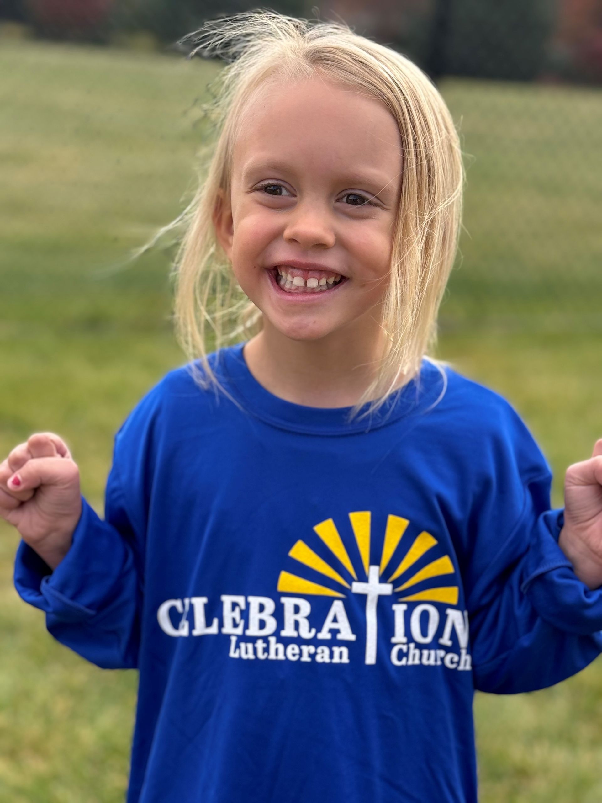 A little girl wearing a blue shirt that says clebration lutheran church