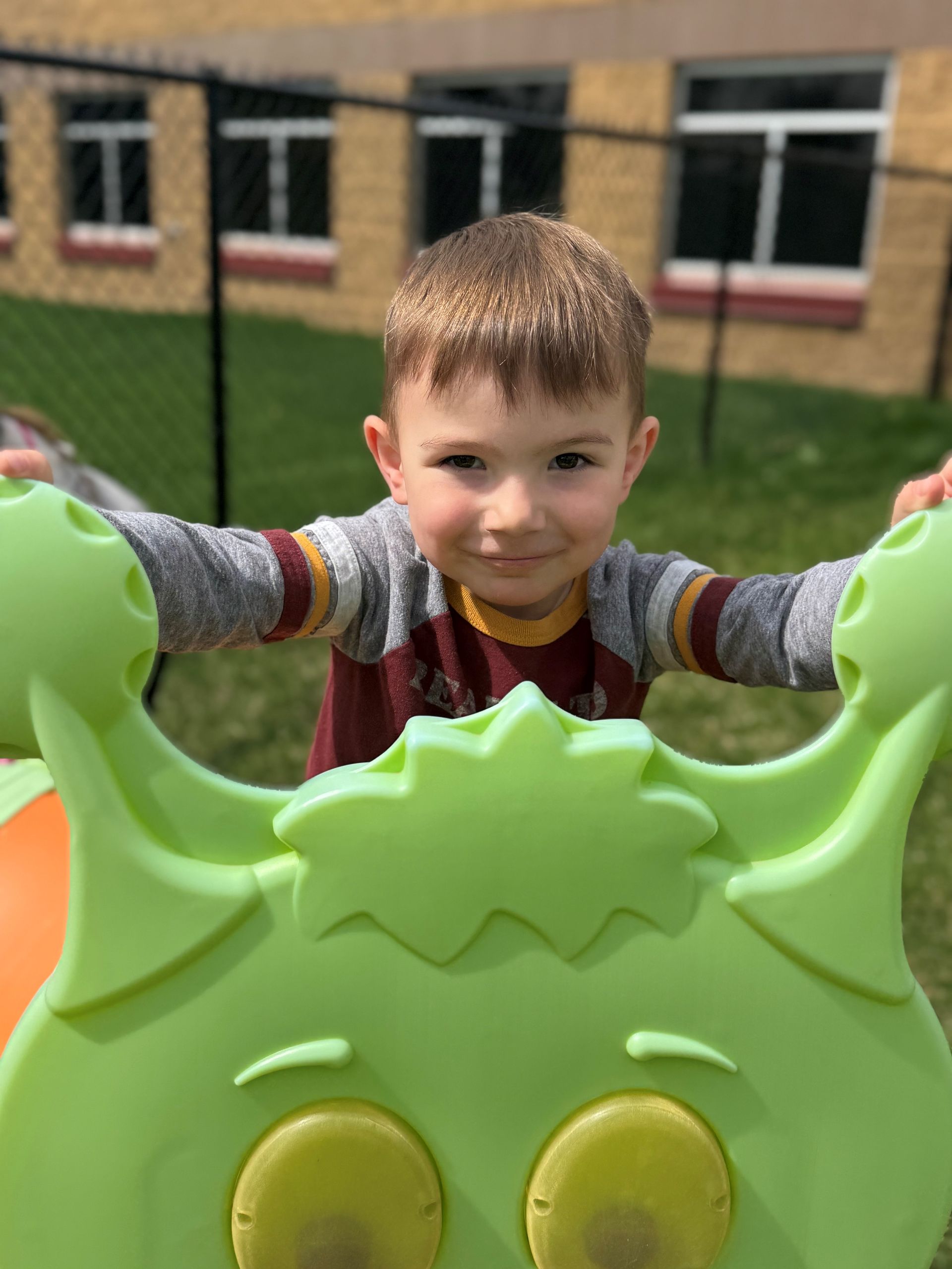 A young boy is standing on top of a green toy.