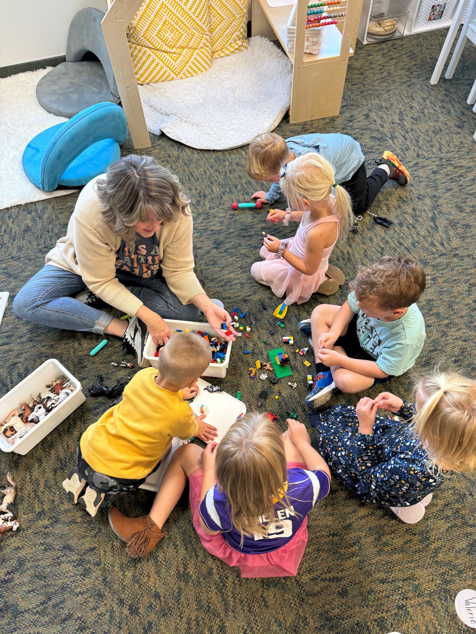 A group of children are sitting on the floor playing with toys.