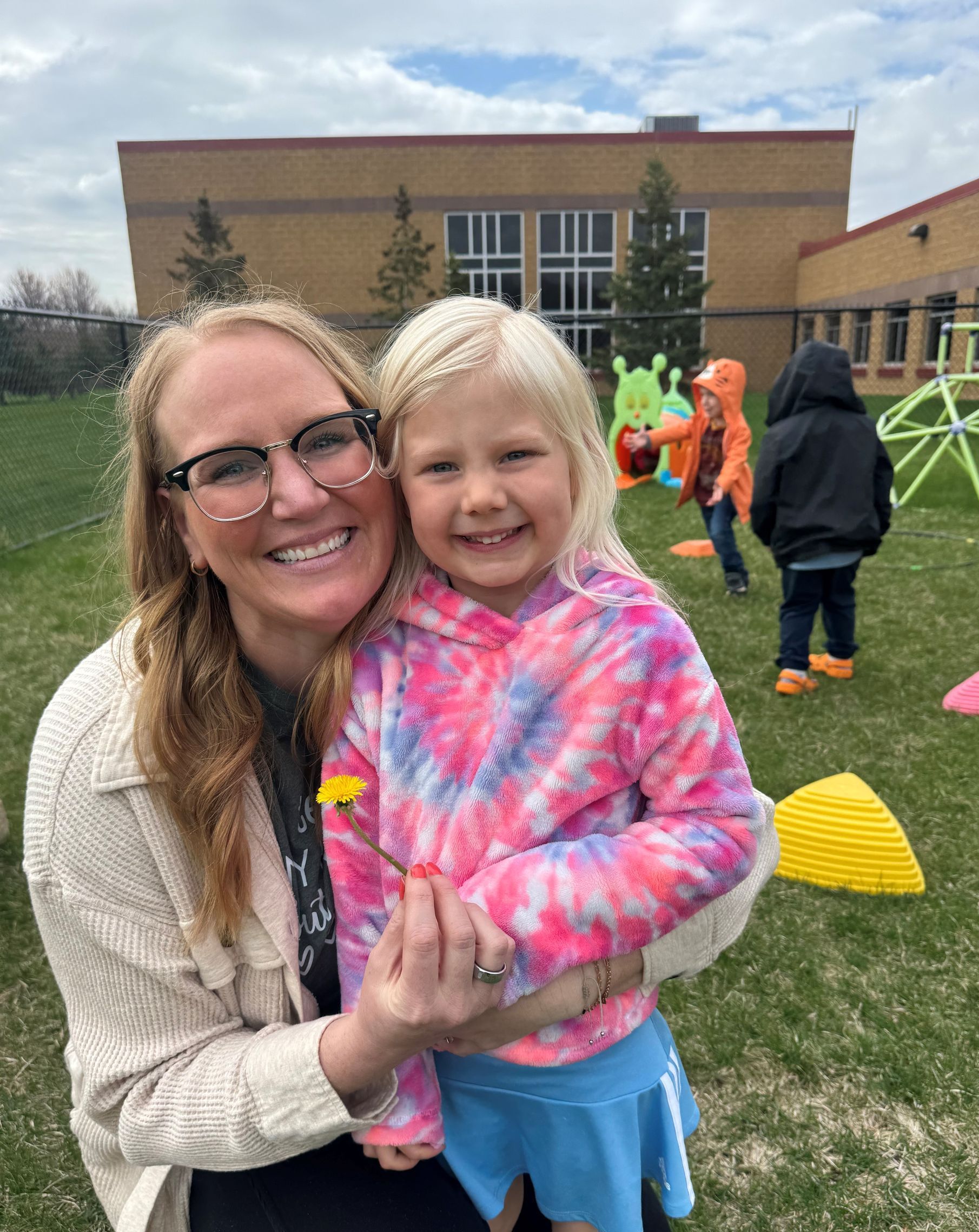 A woman is holding a little girl in her arms in a field.