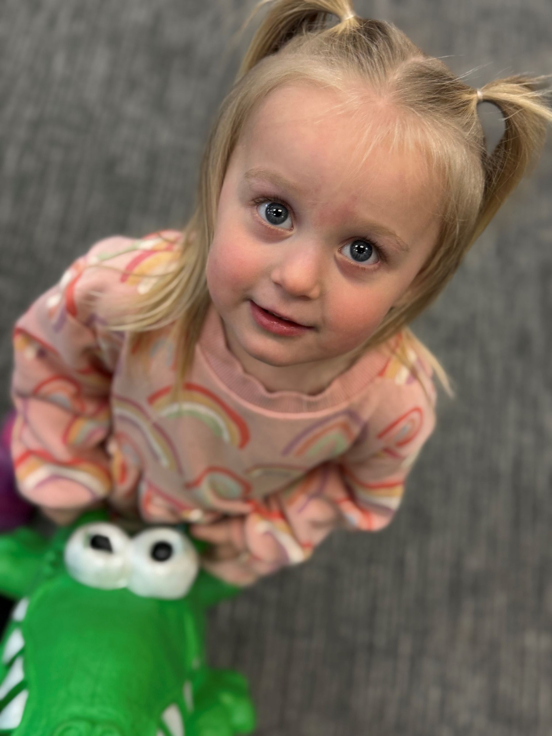 A young boy is standing on top of a green toy.
