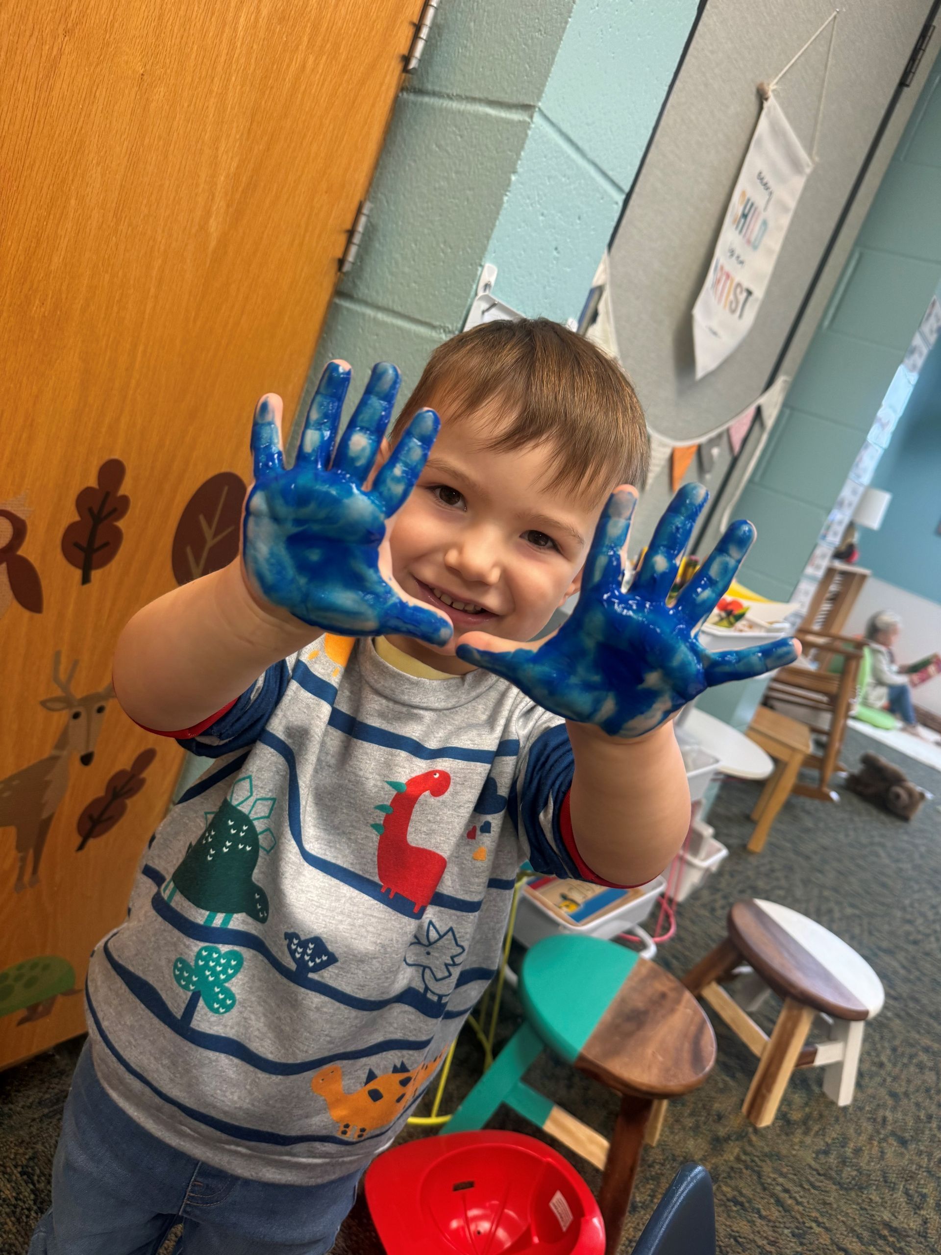 A young boy with his hands covered in blue paint