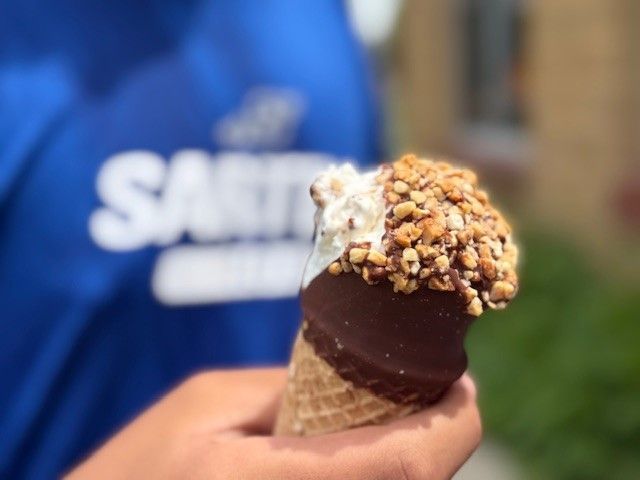 A person holding an ice cream cone in front of a shirt that says santa