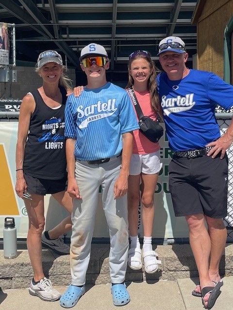A group of people posing for a picture with one wearing a shirt that says Sartell