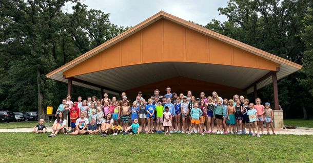 A large group of people are posing for a picture in front of a pavilion.