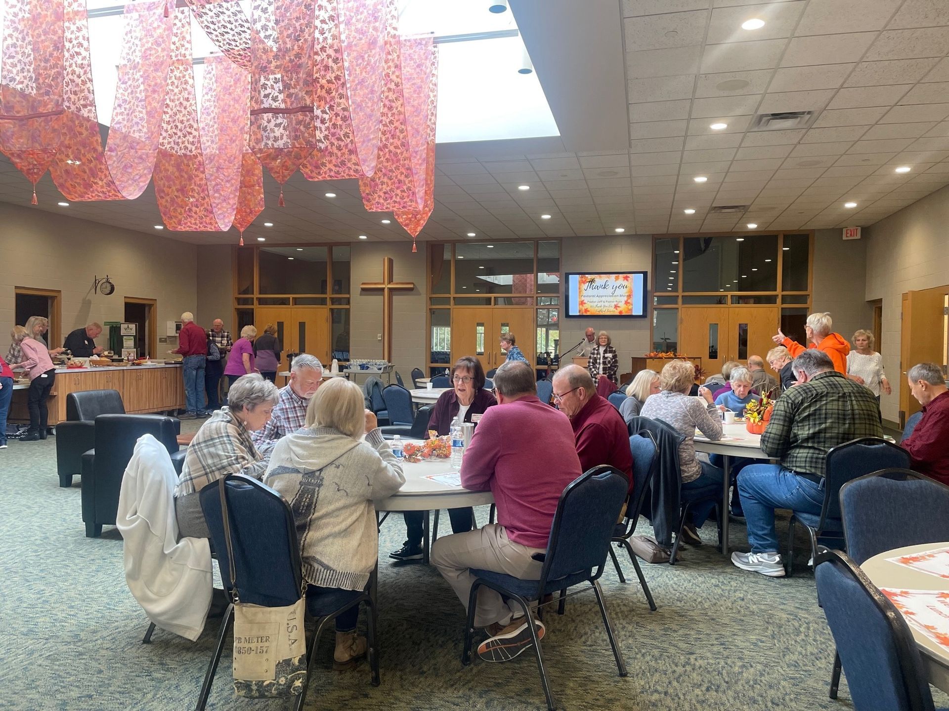 A group of people are sitting at tables in a large room.