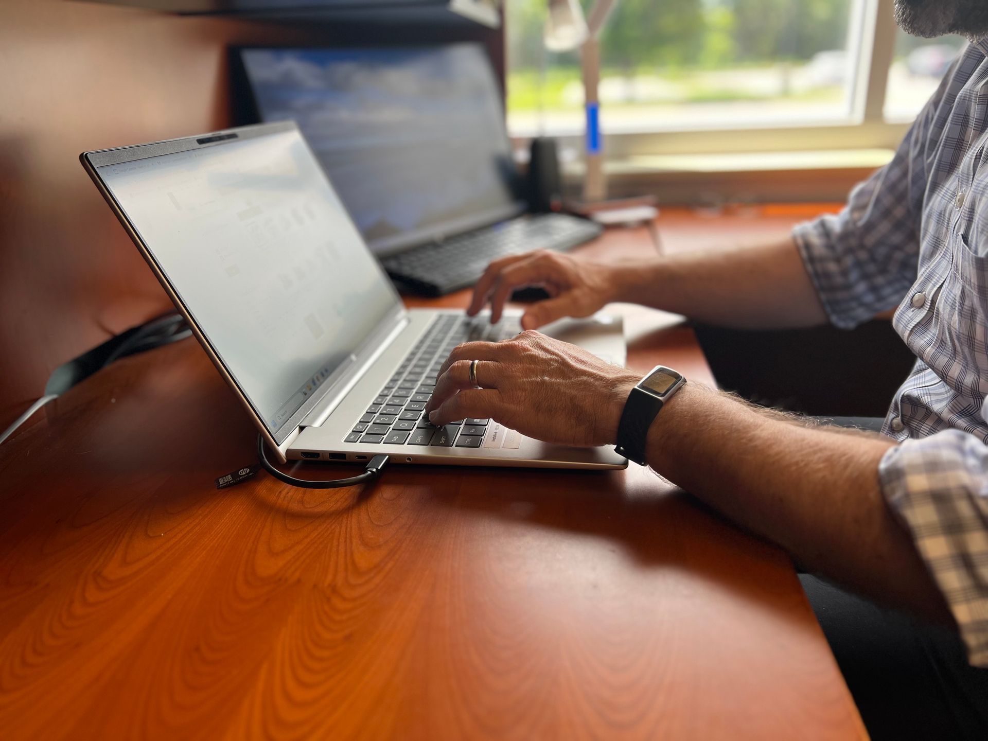 A man is typing on a laptop computer at a desk.