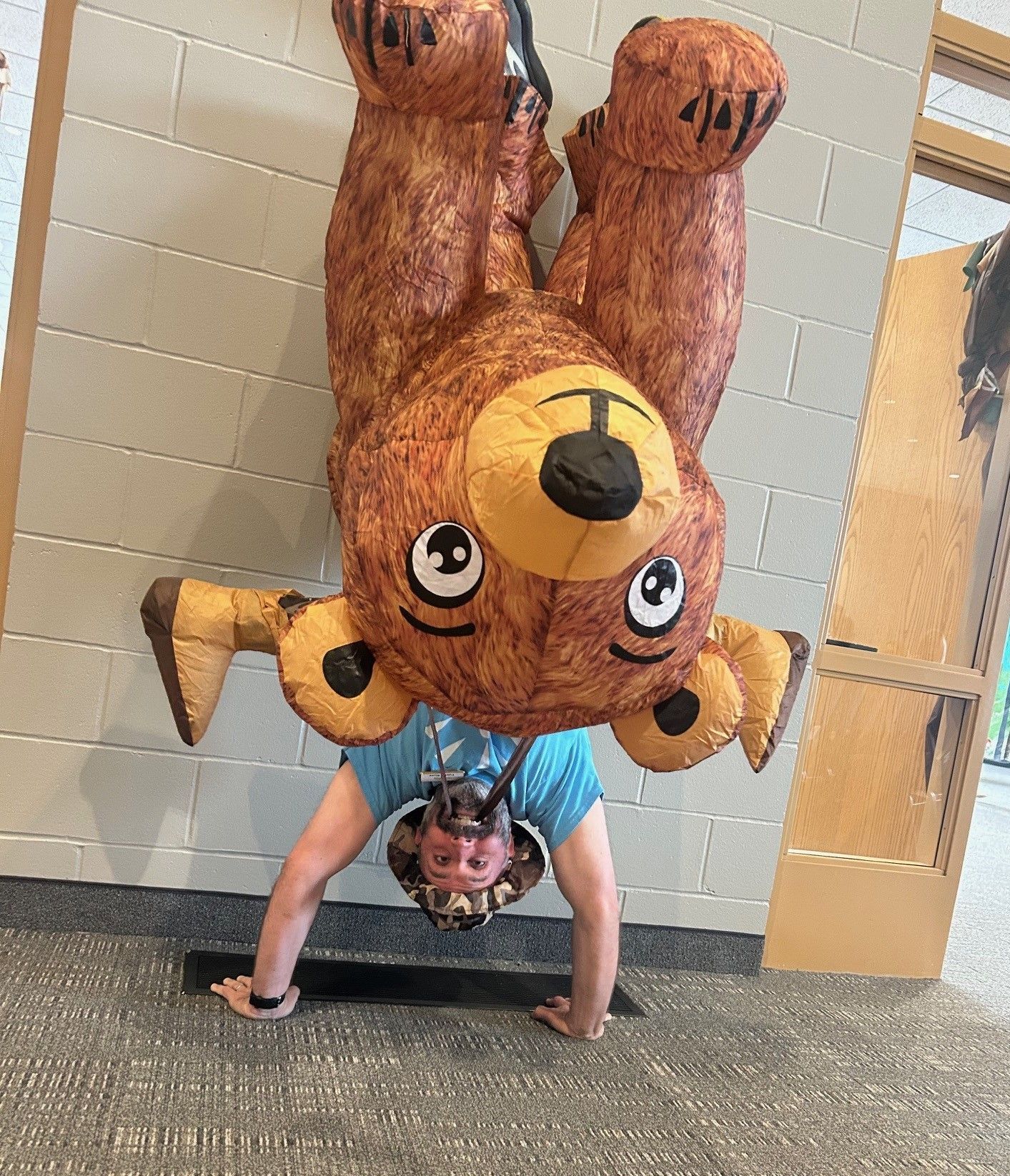A person is doing a handstand while wearing a teddy bear costume