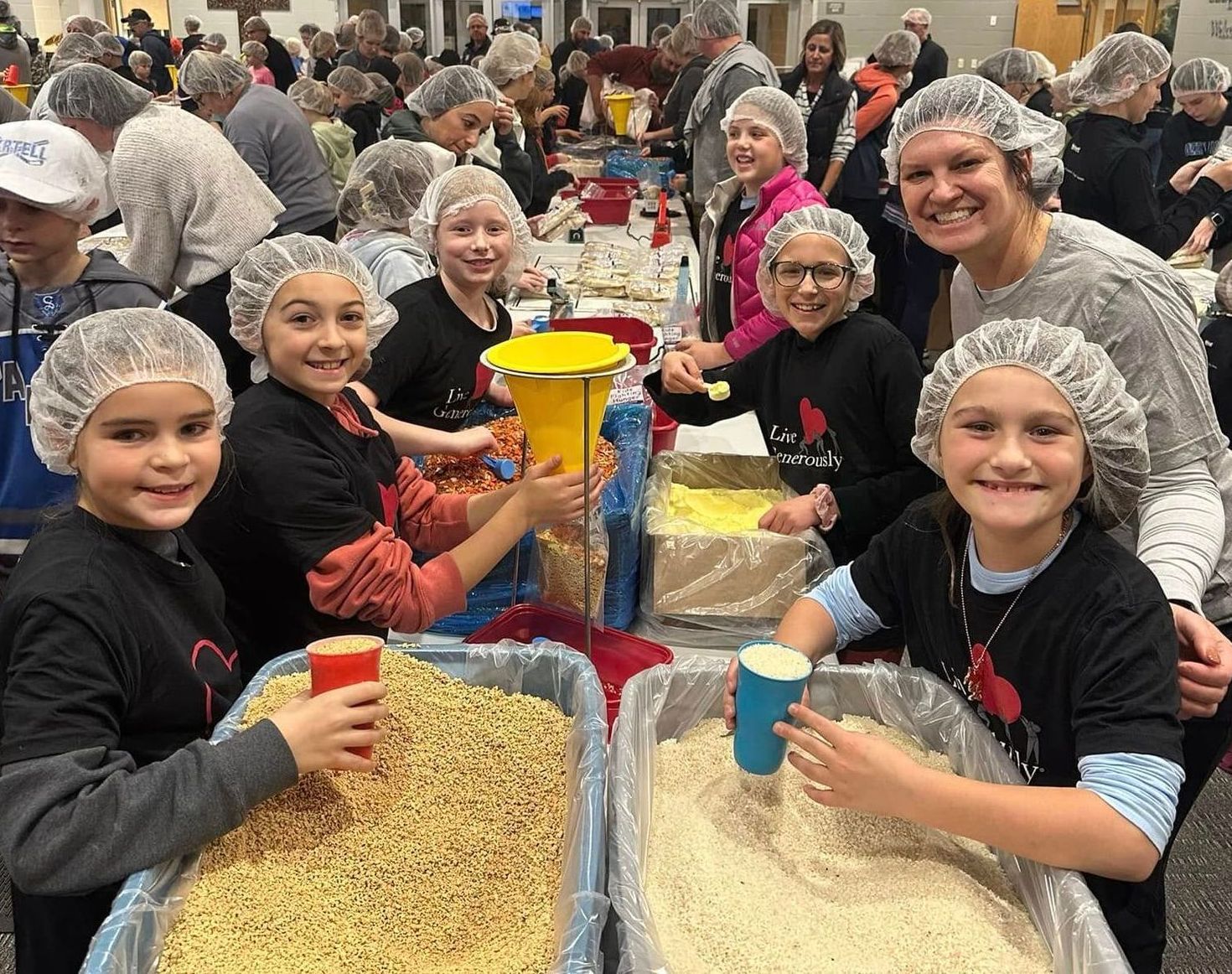 A group of people wearing hair nets are standing around a table.