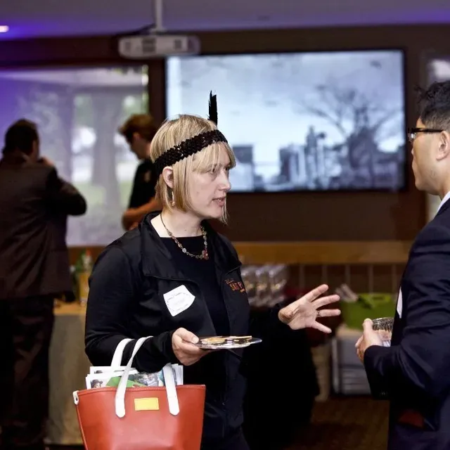A woman in a headband is talking to a man in a suit