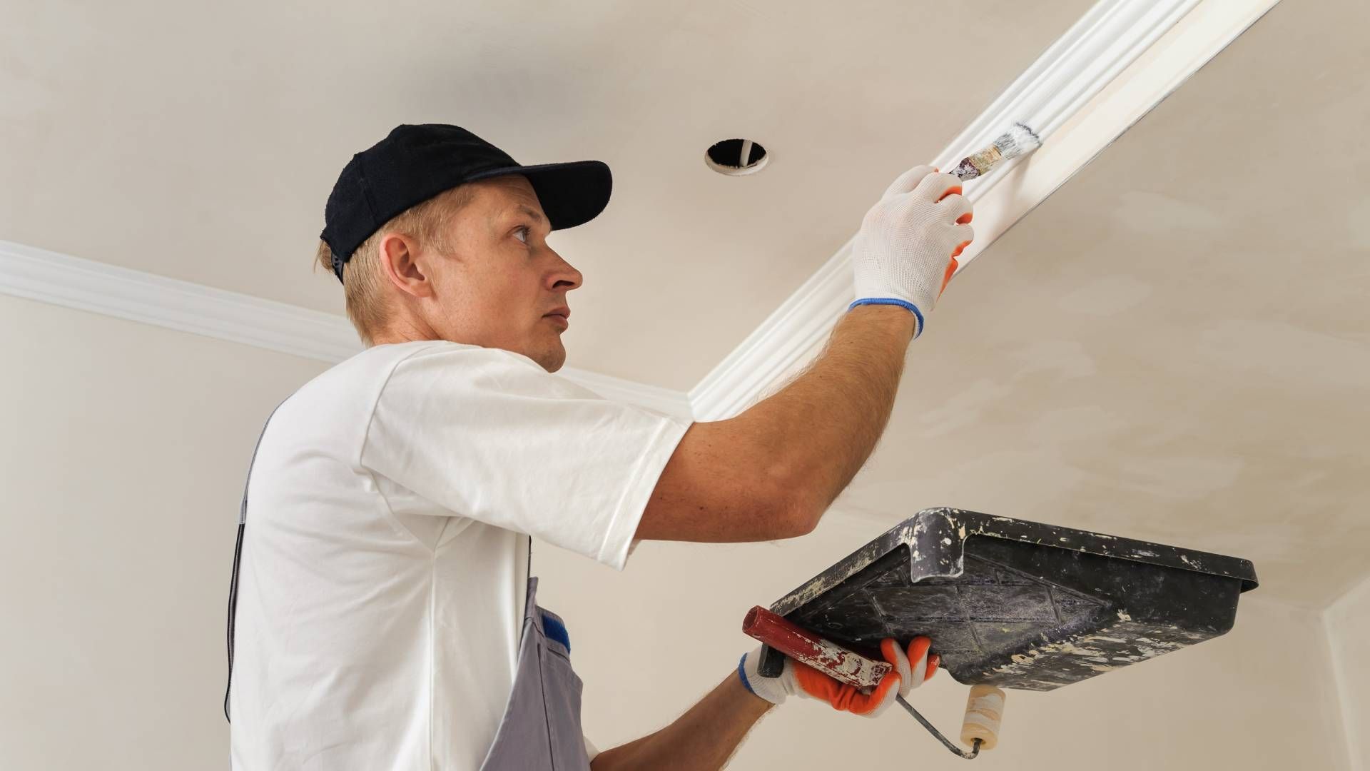 Room with light wood floor, painted walls, window, ladder, and painting supplies.