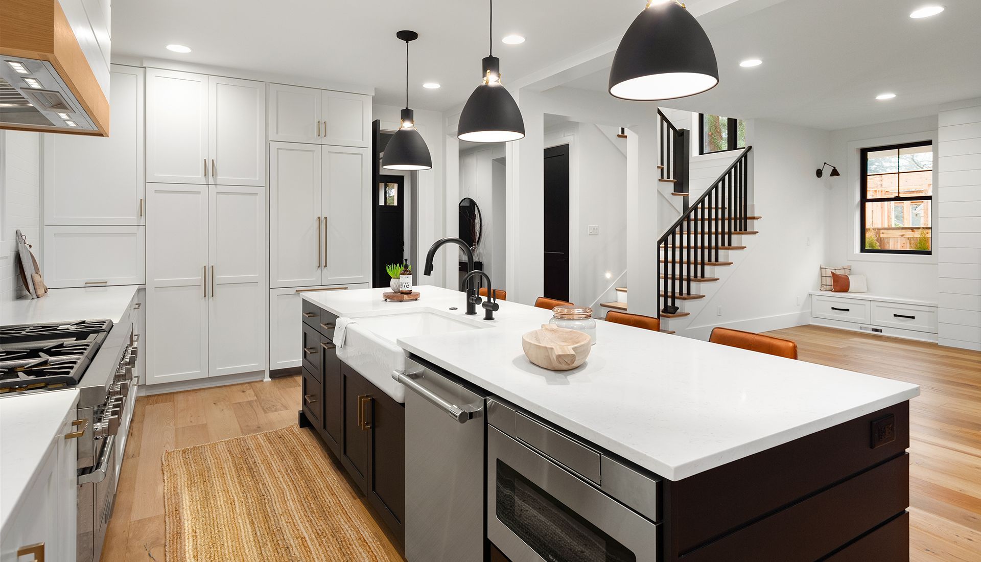Modern kitchen with white cabinets, dark island, and light wood floors.