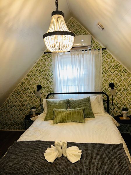 A bedroom with a bed and a chandelier hanging from the ceiling.